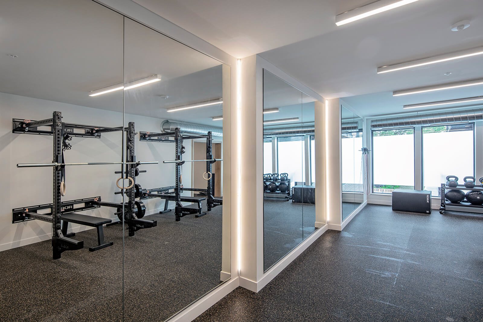 floor to ceiling mirrors in the wakpada minneapolis fitness room reflecting the rogue fitness squat racks